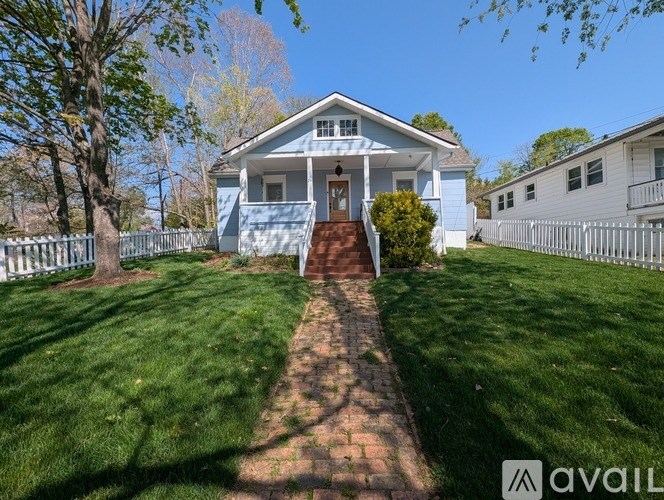 A blue house with a white fence and a brick pathway leading to the front door.