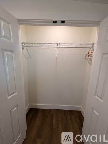 A white closet with a shelf and clothes hanging on it.