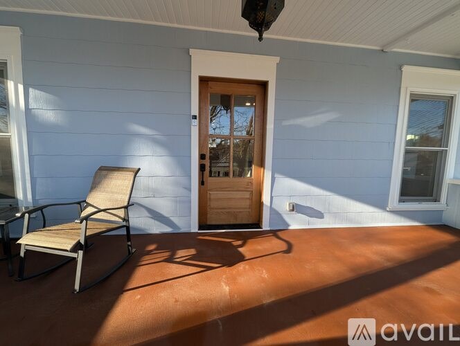 A chair is on a porch with a door in front of it.