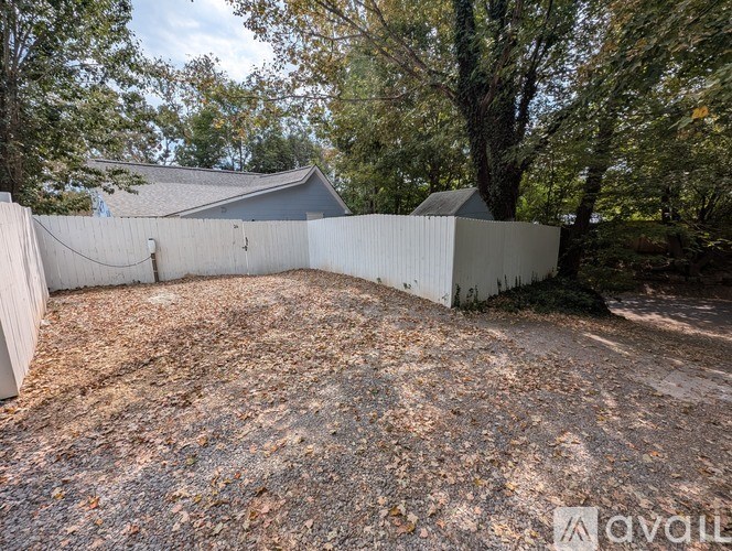 A backyard with a white fence and trees.