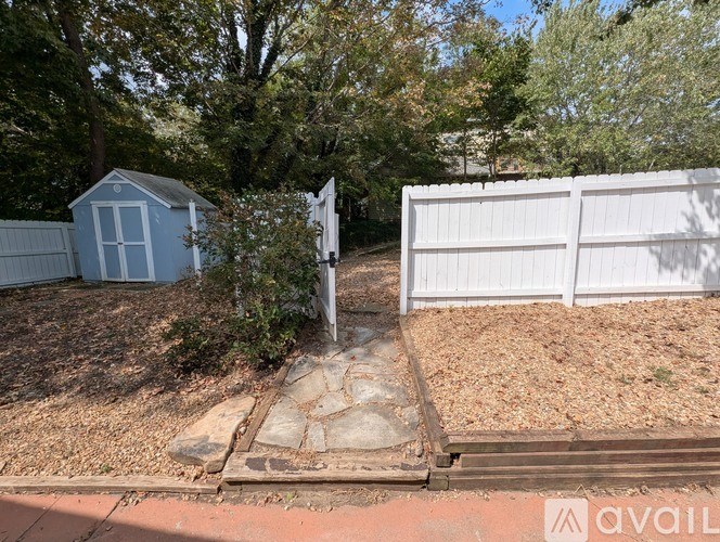 A white fence and a small blue shed are in a yard.