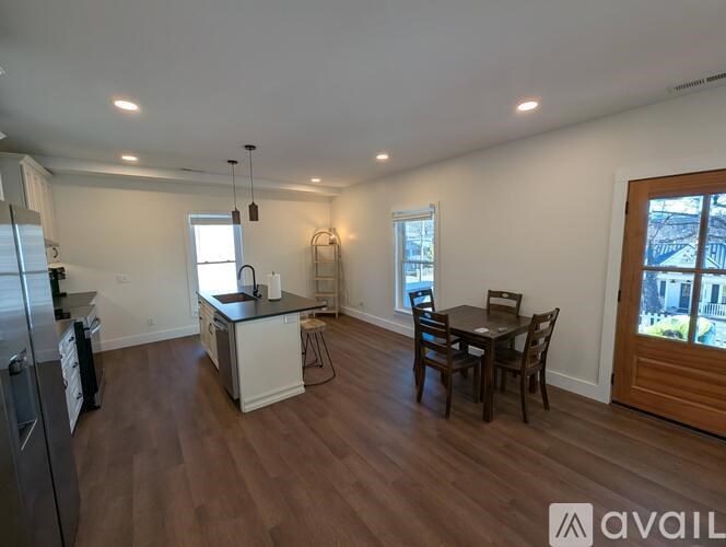 A kitchen with a refrigerator, sink, and dining table with chairs.
