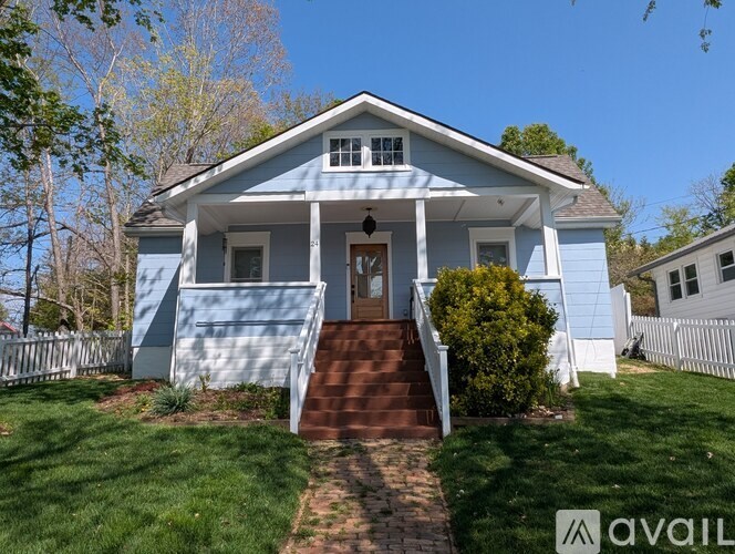 A blue house with a white porch and a brown front door.