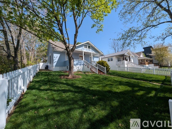 A white picket fence surrounds a house with a tree in the front yard.