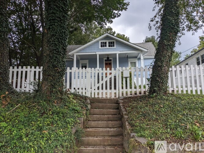 A house with a white picket fence and stairs leading up to the front door.