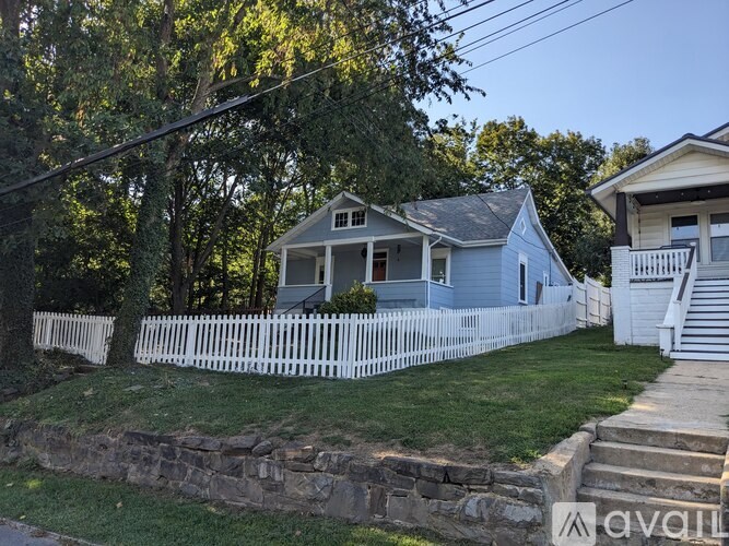 A house with a white picket fence and a stone wall in front.
