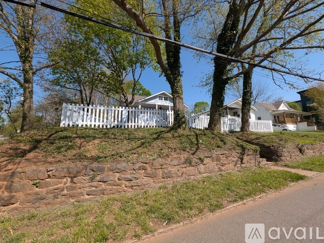 A white picket fence runs along a stone wall in front of a house.