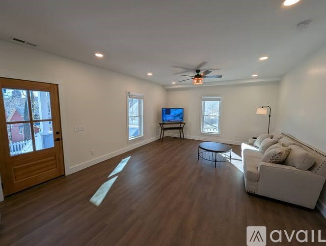 A living room with a couch, a television, and a ceiling fan.