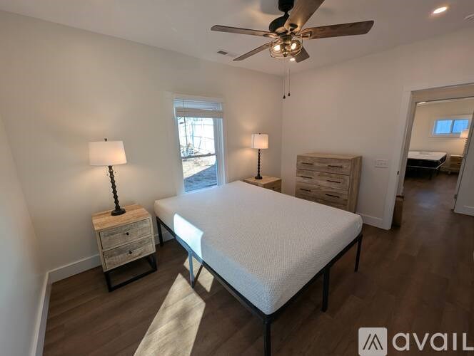 A bedroom with a bed, two lamps, and a ceiling fan.