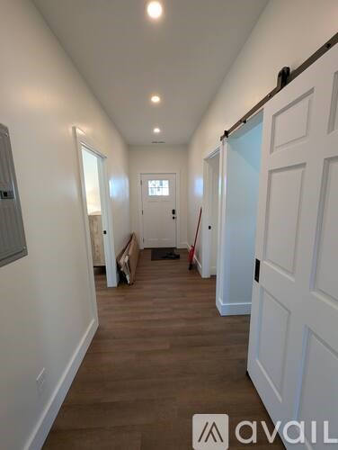 A hallway with white doors and a wooden floor.