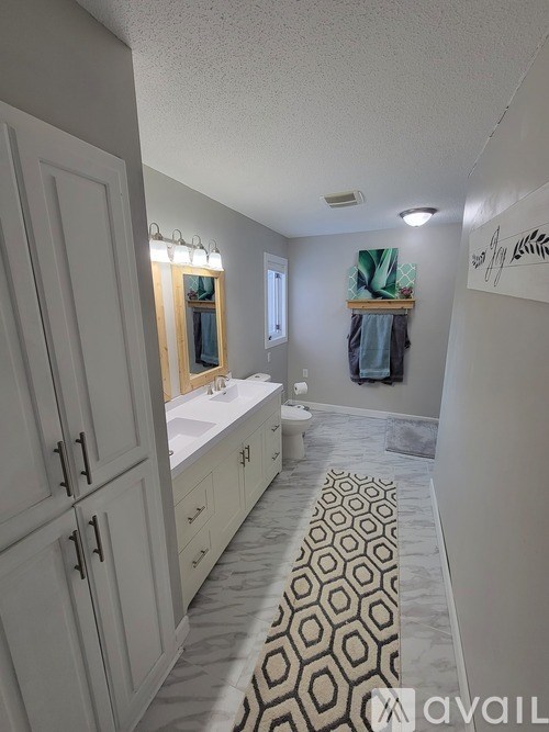 A bathroom with a patterned tile floor and white cabinets.