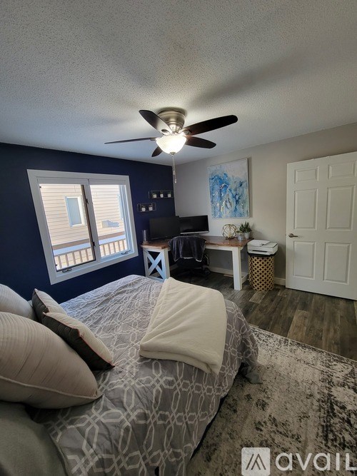 A bedroom with a bed, a ceiling fan, and a window with blinds.