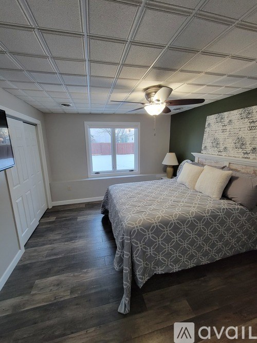 A bedroom with a bed, a ceiling fan, and a window.