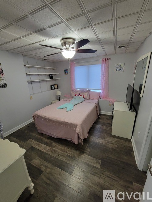 A room with a pink bed and a ceiling fan.