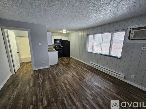 A kitchen with a black refrigerator and white cabinets.
