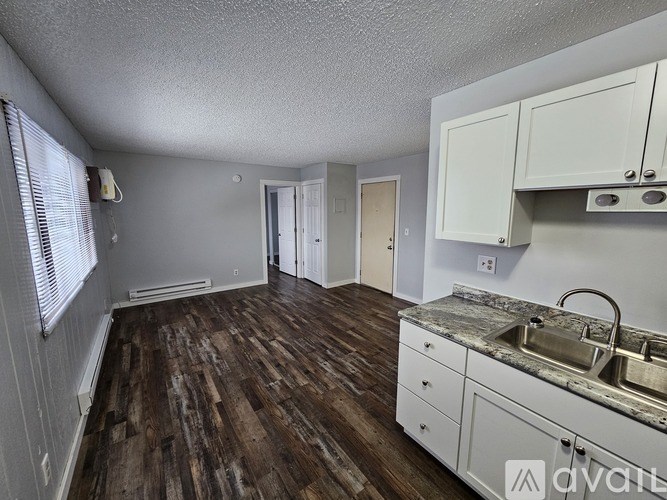 A kitchen with wooden floors and white cabinets.