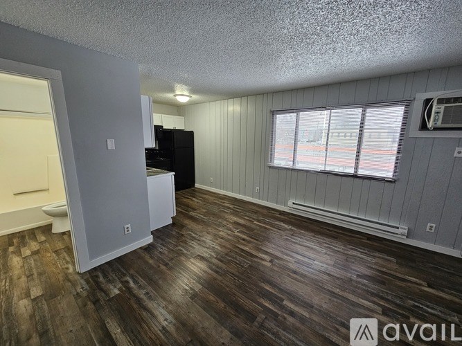 A room with wooden floors and a window with blinds.