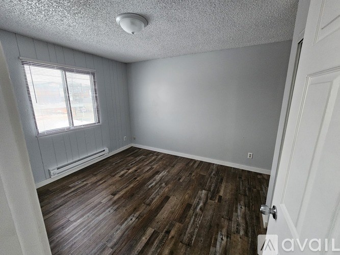 A room with wooden flooring and a window with blinds.