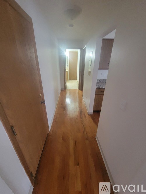 A long hallway with a wooden floor and white walls.