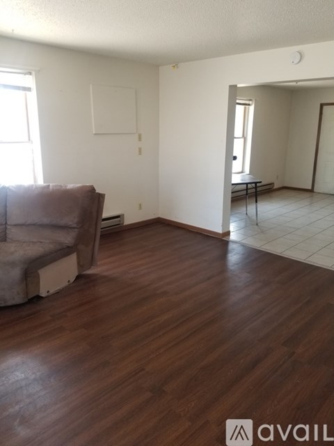 A living room with a brown couch and a white wall.