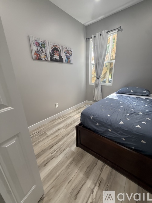 A bedroom with a bed, wooden flooring, and a picture on the wall.
