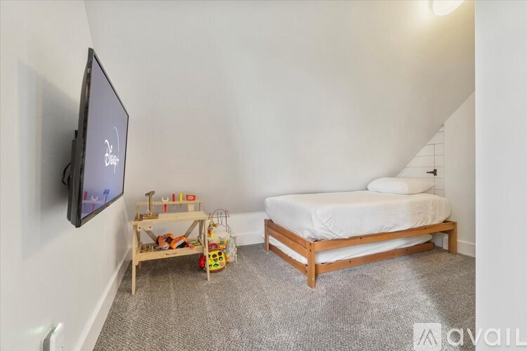 A bedroom with a bed, a TV, and a toy table.