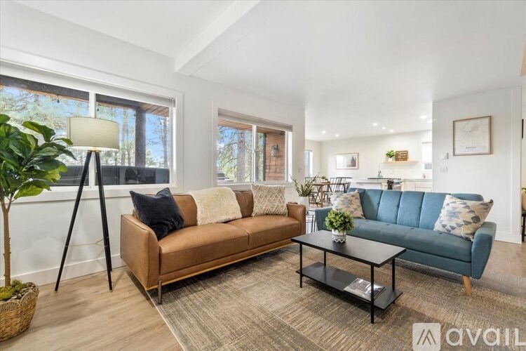 A living room with a brown and blue sofa, a black coffee table, and a large window.