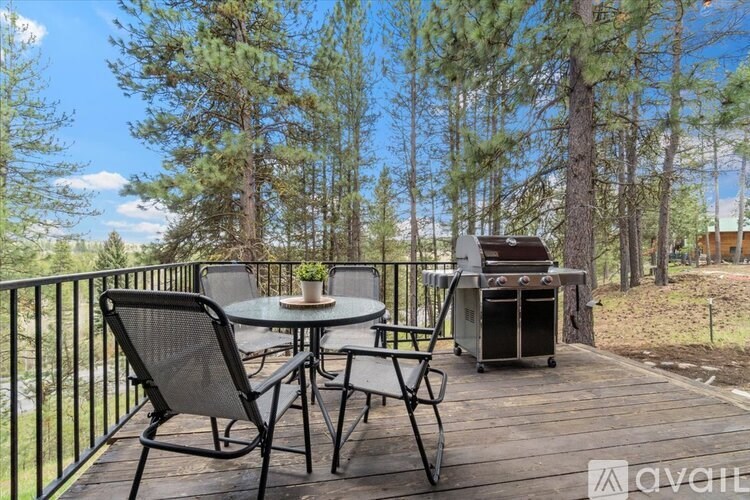 A patio with a table and chairs overlooking a wooded area.