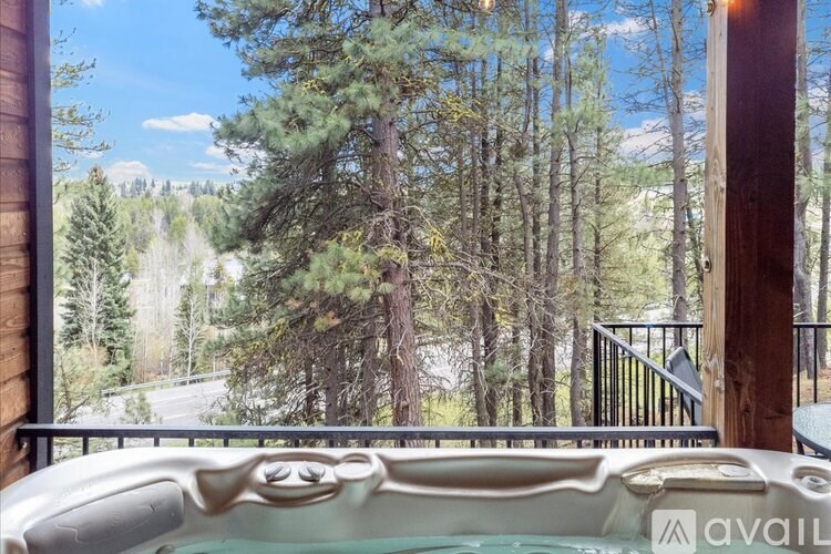 A hot tub is in the foreground of a wooded area.