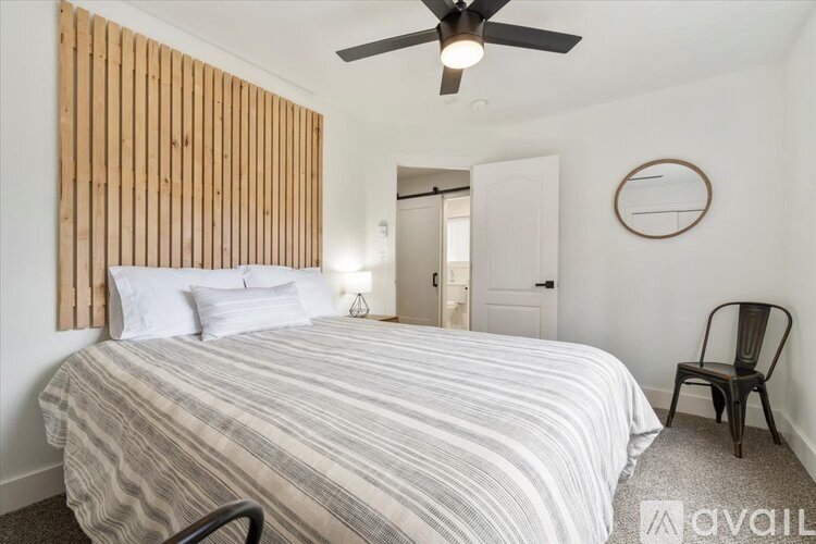 A bedroom with a bed, chair, and wooden paneling on the wall.