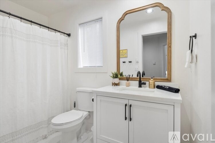 A bathroom with a toilet, sink, and mirror.