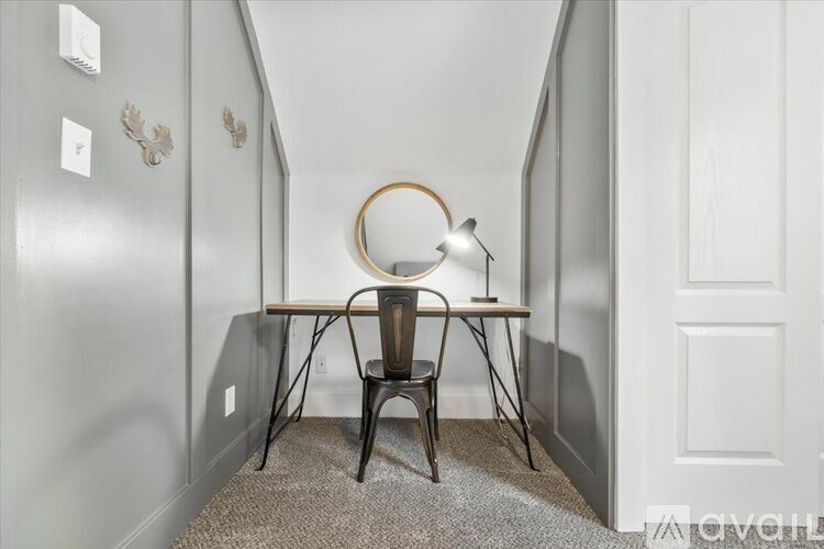 A small table with a chair and a lamp in a narrow hallway.