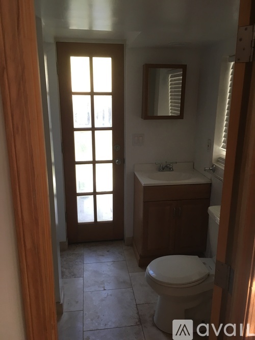 A bathroom with a toilet, sink, and mirror.