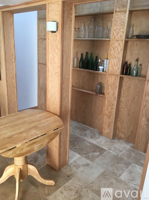 A wooden table and shelves with bottles on them.