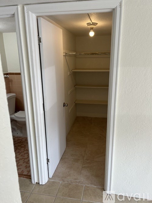 A white door is open to a small, empty room with a light on.