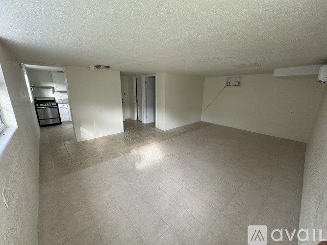 A spacious room with a kitchen area in the background.