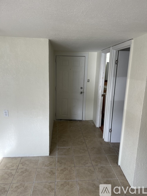 A hallway with a white door and a tiled floor.