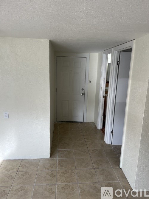 A hallway with a white door and a tiled floor.
