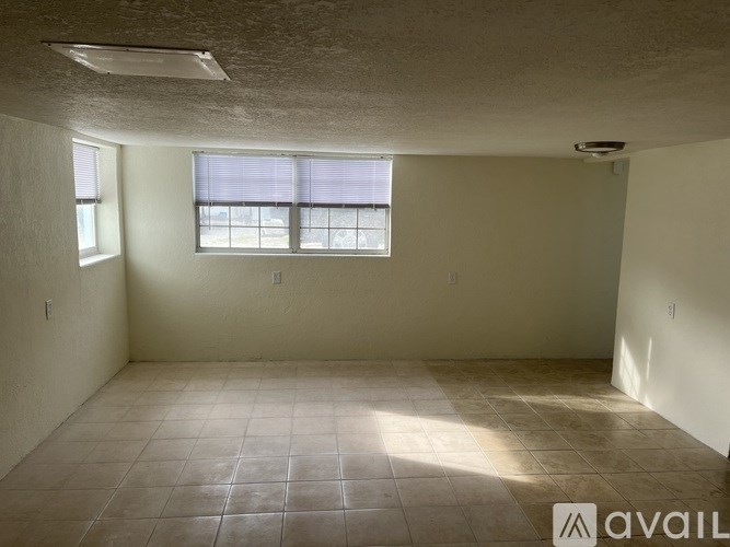 A room with tiled flooring and a window with blinds.