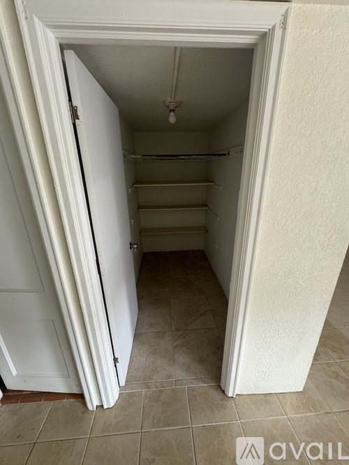 A white door is open to a small, empty room.