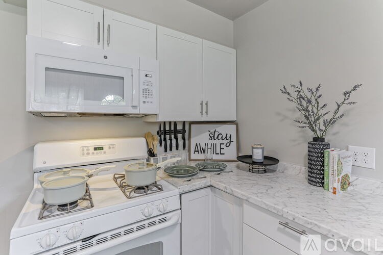 A white kitchen with a stove, microwave, and cabinets.