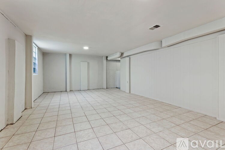 A spacious room with white walls and tiled flooring.