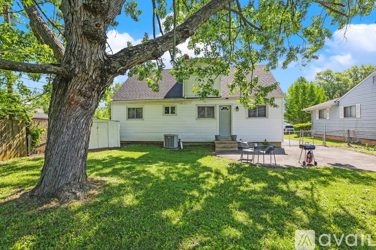 A tree in a yard with a house in the background.