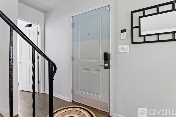 A white door with a glass panel is closed and there is a black railing on the left side.
