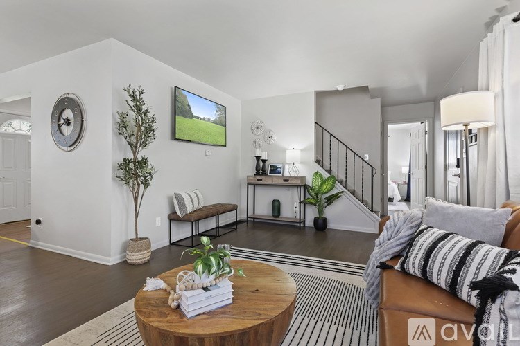 A living room with a couch, a coffee table, and a TV on the wall.