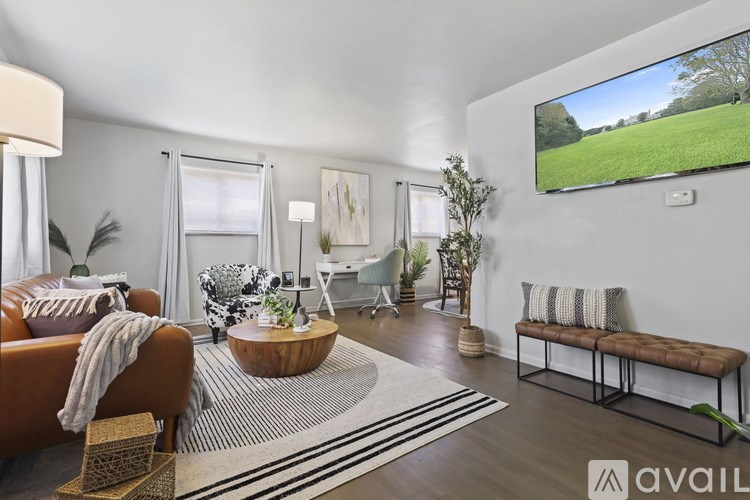 A living room with a brown sofa, a wooden coffee table, and a television displaying a green field.
