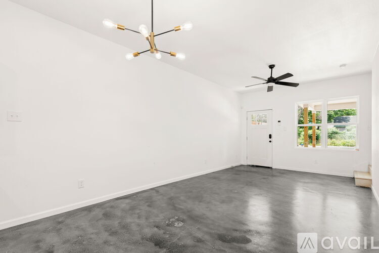A spacious room with a ceiling fan and a window showing a view of trees and a building.