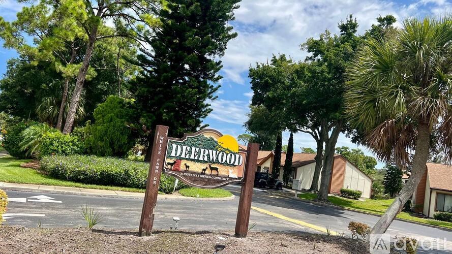 A sign for Deerwood stands in front of a row of houses.