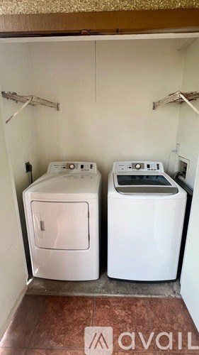 Two white front loading washing machines in a small room.