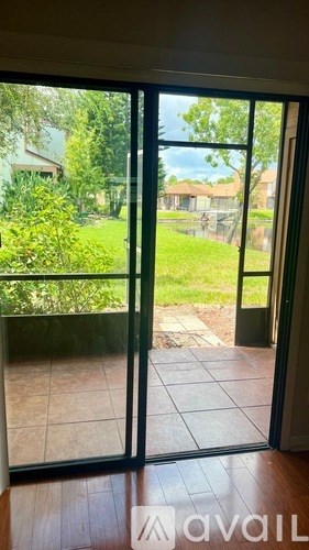 A glass door with a view of a green lawn and a house.